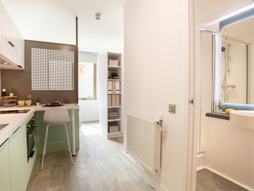 A white and green kitchen with a white chair and a white radiator.