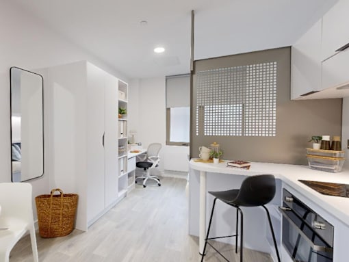 A modern kitchen with a white countertop and a black bar stool.