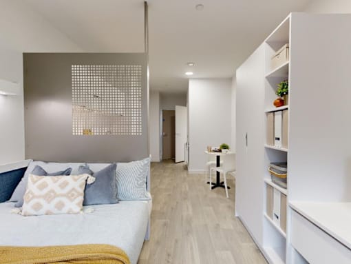 A bedroom with a bed, a desk, and a chair.