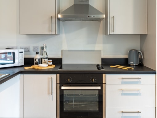 a kitchen with white cabinets and a black counter top and a oven and a microwave