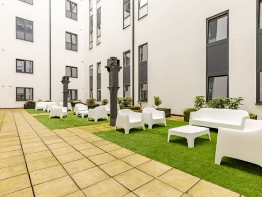 a courtyard with lawn chairs and tables in front of a building