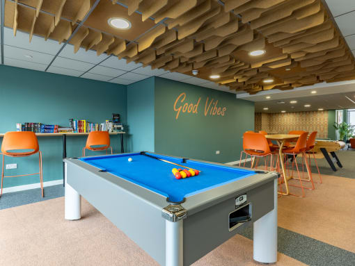 a pool table in a room with a bar and chairs