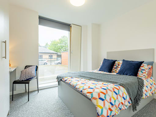 A bedroom with a bed, chair, and window.