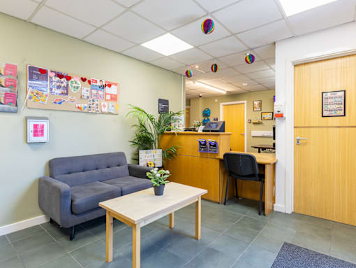 A waiting room with a couch, chair, and a table.