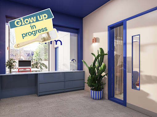 A sign that says "Glow up in progress" hangs over a desk in a room.
