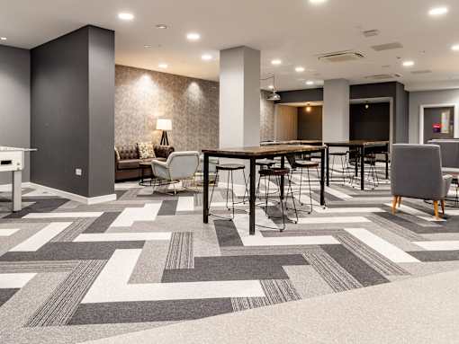 A modern office space with a patterned carpet and a long table with chairs.
