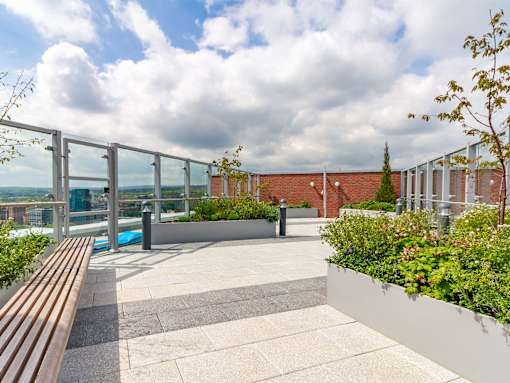 A patio with a bench and a pool with a metal railing.