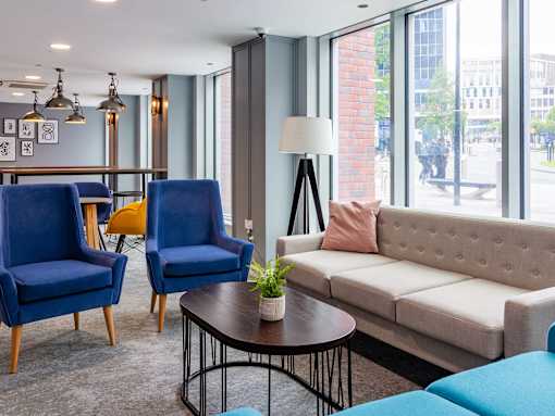 A living room with a sofa, two chairs, and a table with a plant on it.