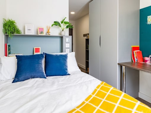 A bed with a white comforter and a yellow and white pillow.