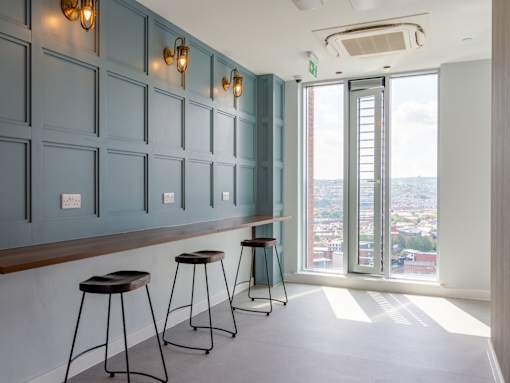 Three bar stools are placed in front of a wall with lights.