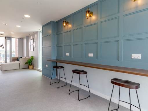 A room with a blue wall and a bar area with stools.