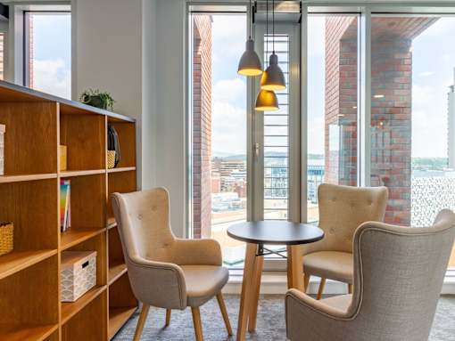 A room with a table, two chairs and a bookshelf.
