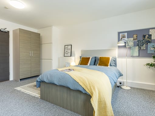 A bedroom with a bed, a nightstand, and a wardrobe.