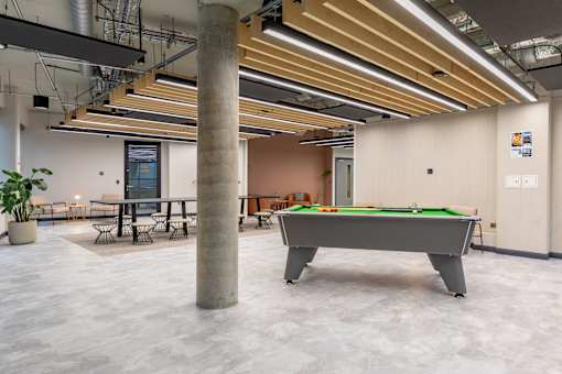 A room with a pool table and a pillar.