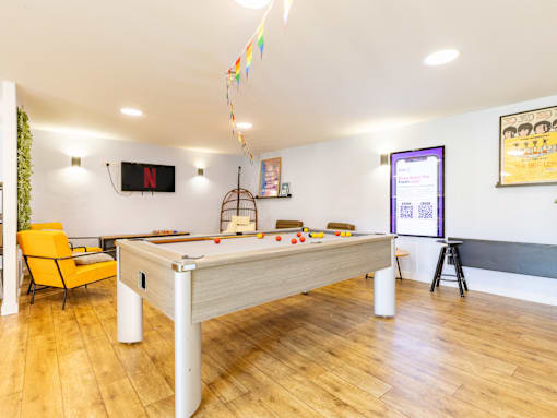 A room with a pool table and a chair.