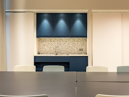 A conference room with a table and chairs and a counter with a backsplash.