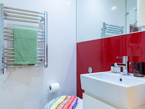 A white sink with a green towel on a towel rack.