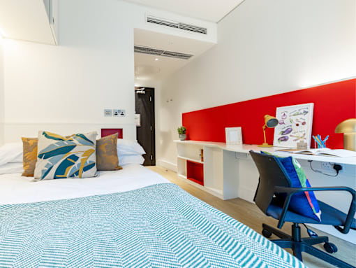 A room with a bed, desk, and chair.