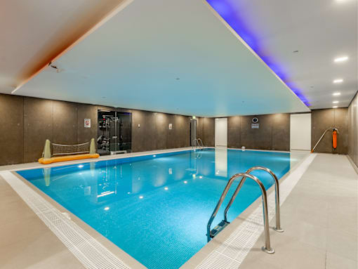 A large indoor swimming pool with a diving board and a no-entry sign.