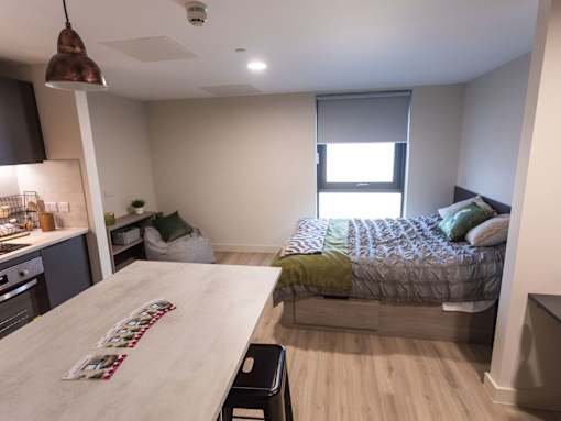 A kitchen with a table and a bed in a room.