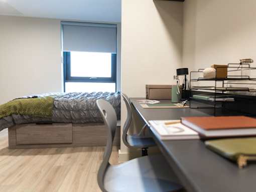 A bedroom with a bed, desk, and chair.