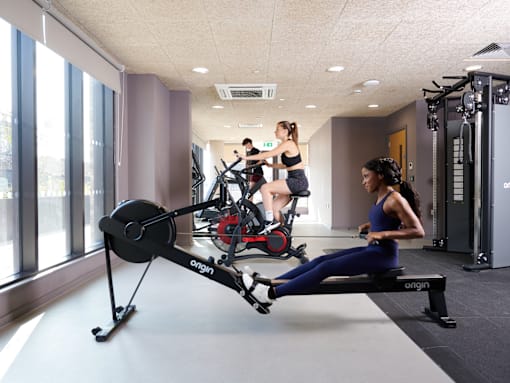 A woman is working out on an Orgin rowing machine in a gym.