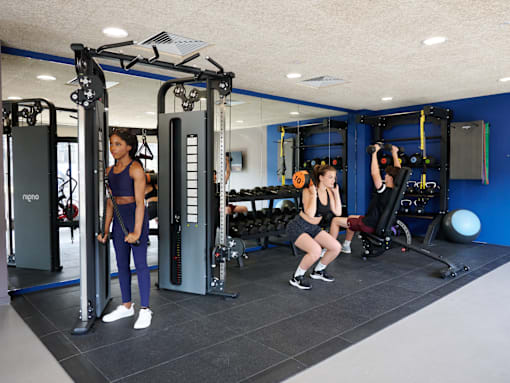 A woman is working out in a gym with a squat rack and a woman is doing squats.