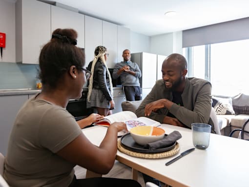 A group of people are gathered around a table in a modern kitchen.
