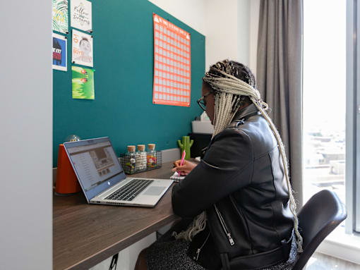 A woman with a scarf on her head is working on a laptop.