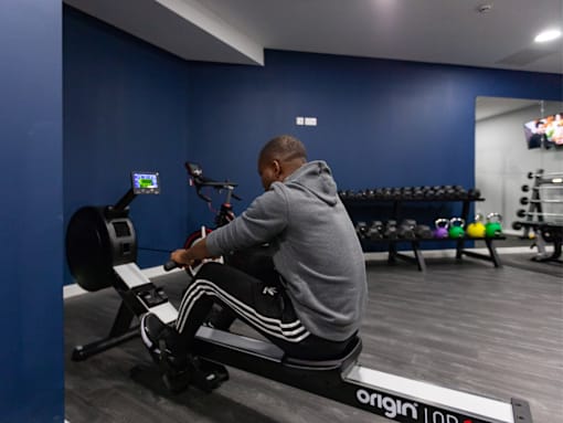 A man is working out on a rowing machine in a gym.