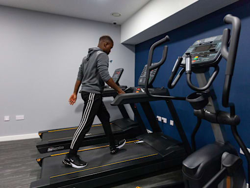 A man is walking on a treadmill in a gym.