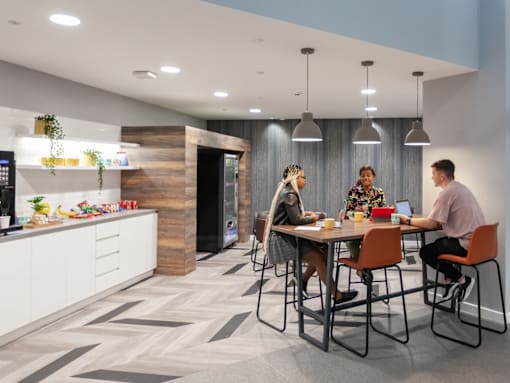 Three people are sitting at a table in a modern kitchen.