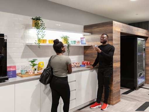 Two people standing in a modern kitchen talking to each other.