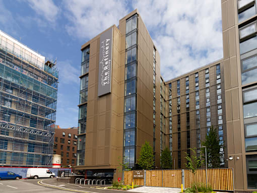 External imagery of The Refinery, a tall building with large glass windows.
