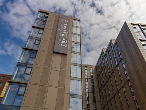 The Refinery building is a modern structure with a brown facade and glass windows.