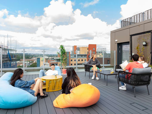 A group of people are sitting on a rooftop terrace.