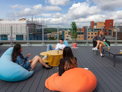 Four people sitting on bean bags on a wooden deck.