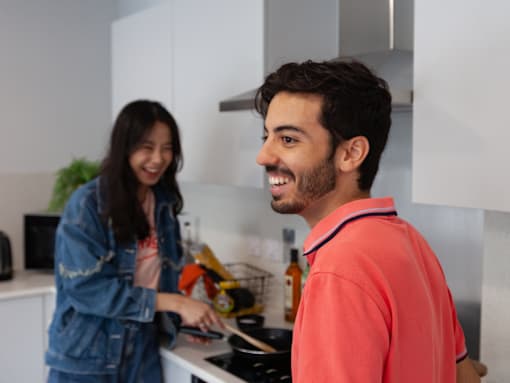 A man and a woman are cooking together in a modern kitchen.