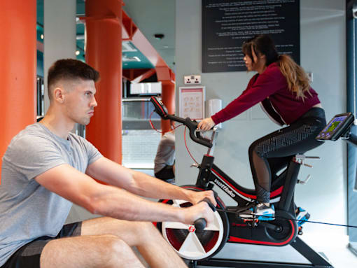 A man and a woman are exercising on stationary bikes in a gym.