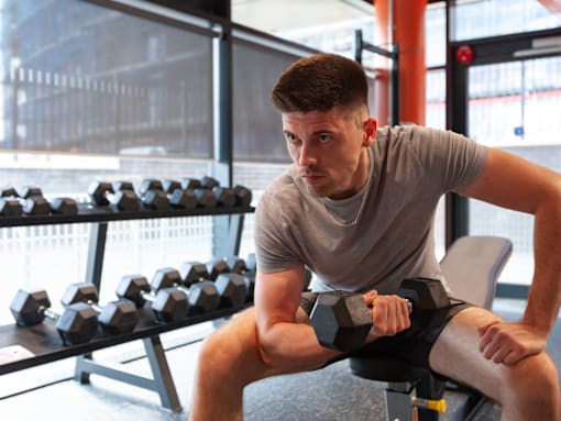 A man is working out with dumbbells in a gym.