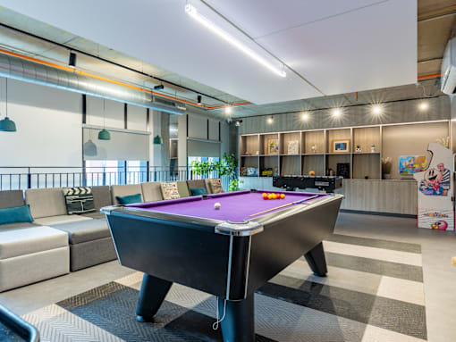 A pool table is in the middle of a room with a couch and a coffee table.