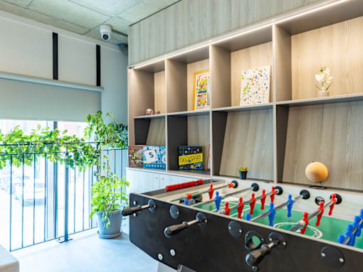 A foosball table is in the middle of a room with a green plant to the left.