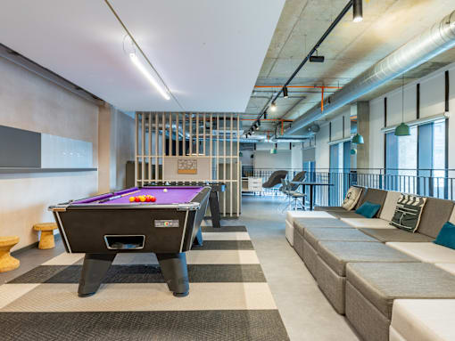 A pool table is in the middle of a room with a couch and a chair.