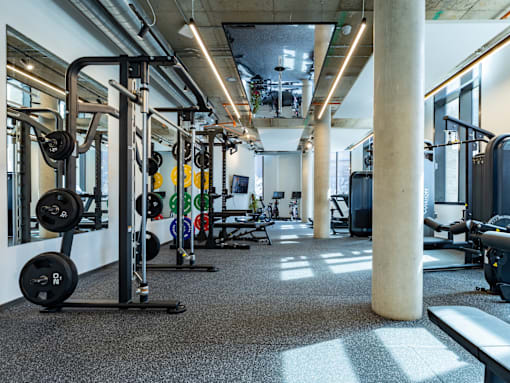 A gym with a variety of equipment including weightlifting machines and dumbbells.