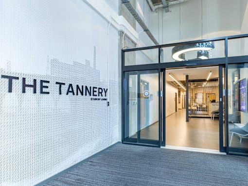 The Tannery student lounge is a modern space with a glass door entrance.