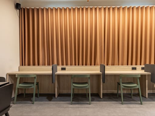 A room with a long table and chairs with a curtain in the background.