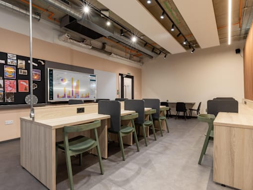 A room with a long table and chairs with a screen on the wall.