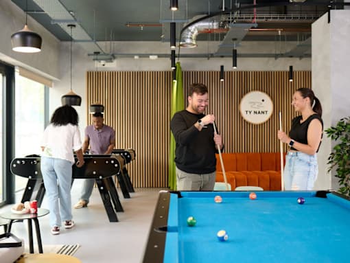 A man is playing pool with two women in a room with a pool table.