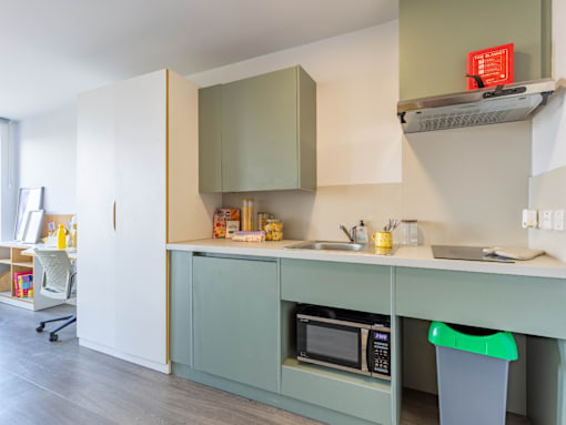 A kitchen with green cabinets and a white counter.