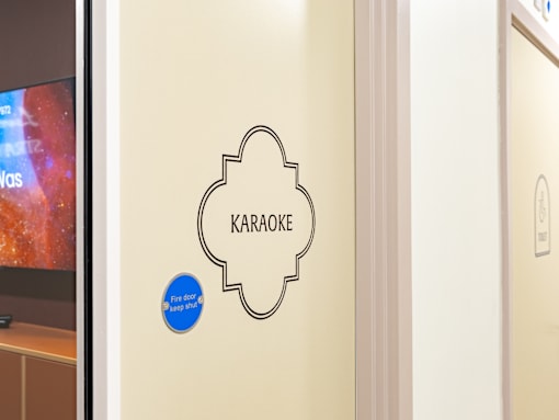 A wall with a Karaoke sign and a blue circle with the words "Fire door keep shut".